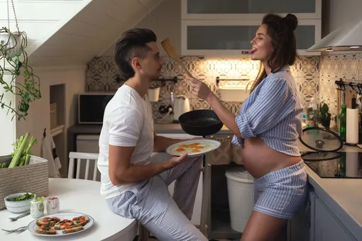 Беременная жена заигрывает с мужем со сковородкой с яичницей в руке