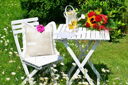 садовый стул с подушкой, стол, графин,цветы, лейка, отдых под солнцем в саду