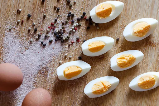 Дольки яиц вкрутую, соль и перец на столе