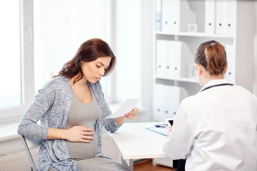 Беременная на приеме у доктора смотрит рецепт