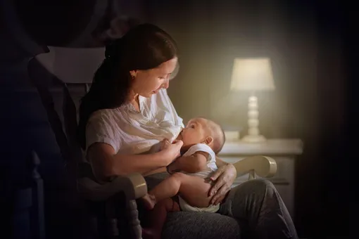 Мама кормит грудью малыша в кресле-качалке